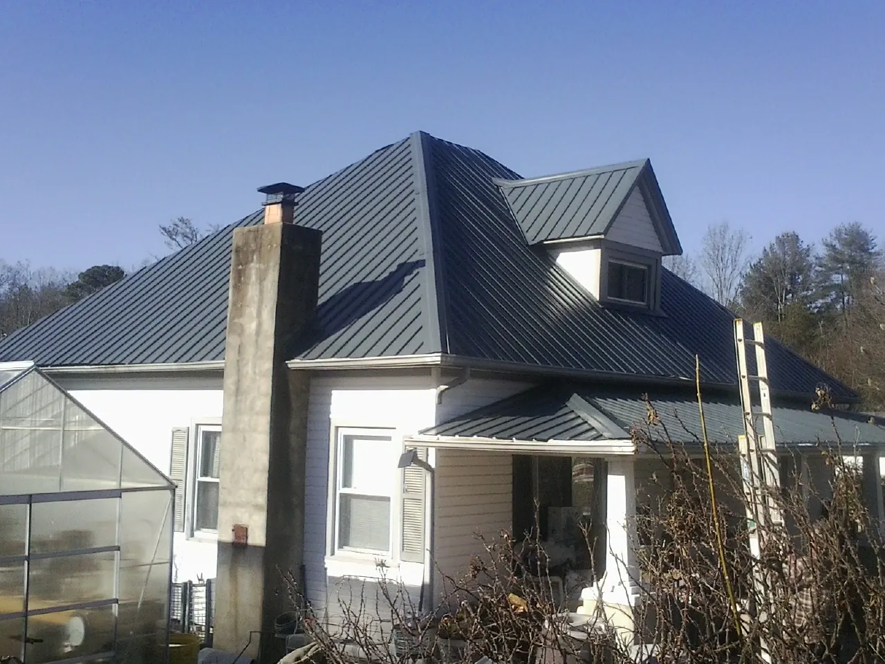 Dark blue standing seam metal roof on a white farmhouse with dormer — Slate & Tile Roof Repair by Roofing Brothers in Walland