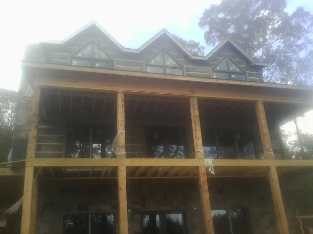 Dormers and porch framing on a large log home under construction — Roof Coating work by our crew in Walland
