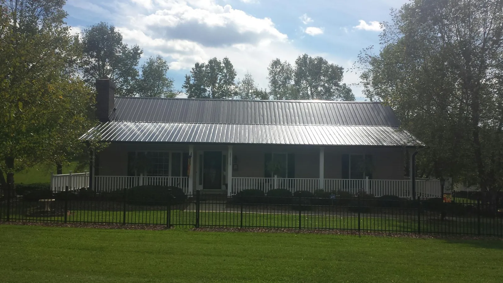 Gray metal roof on a brick ranch with a full width front porch — Gutter Guard Installation work by our crew in Walland