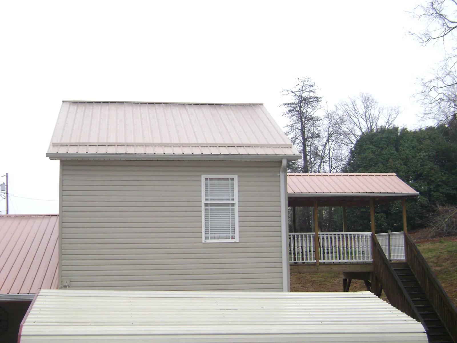 Tan metal roofs on a two story addition and attached porch, from a Roof Replacement job in Walland