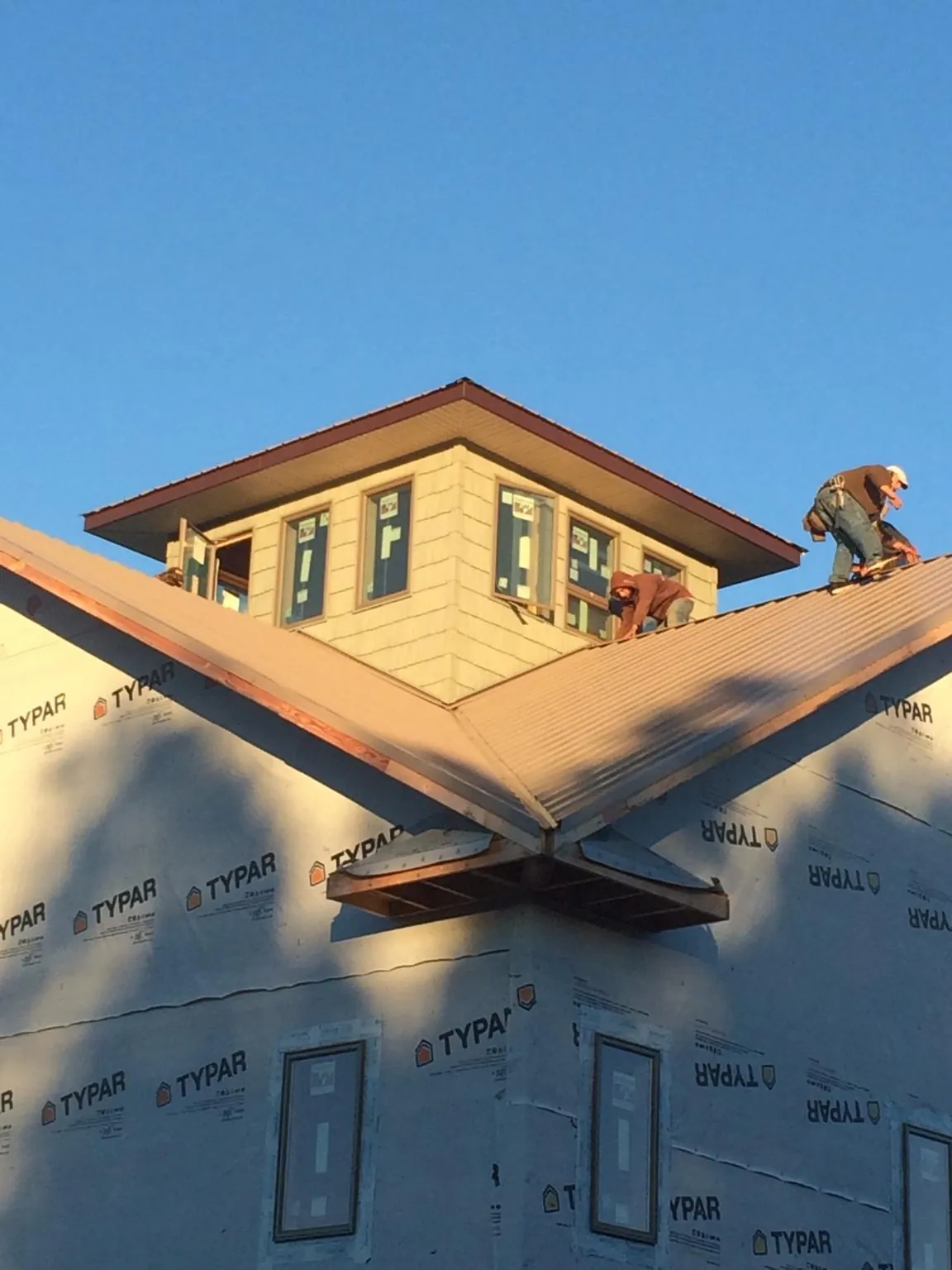 Roofers working around a rooftop cupola on a new metal roof at sunset — Roof Waterproofing in Walland by Roofing Brothers